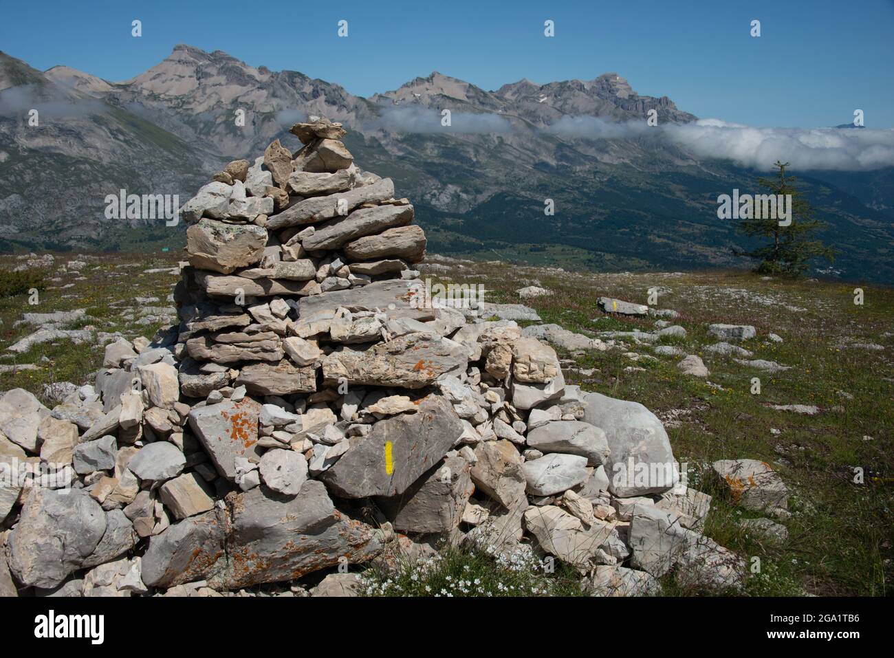 Pile de pierres ou cairn , dans les alpes françaises avec des sommets de montagne et des nuages à distance. Banque D'Images