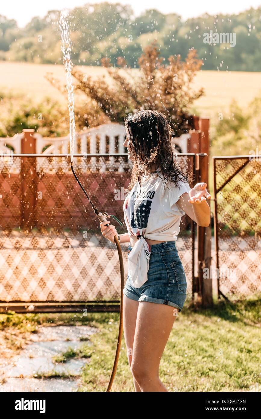 fille avec une fontaine dans le jardin au coucher du soleil. chaud été, chemise humide. Drapeau des États-Unis Banque D'Images