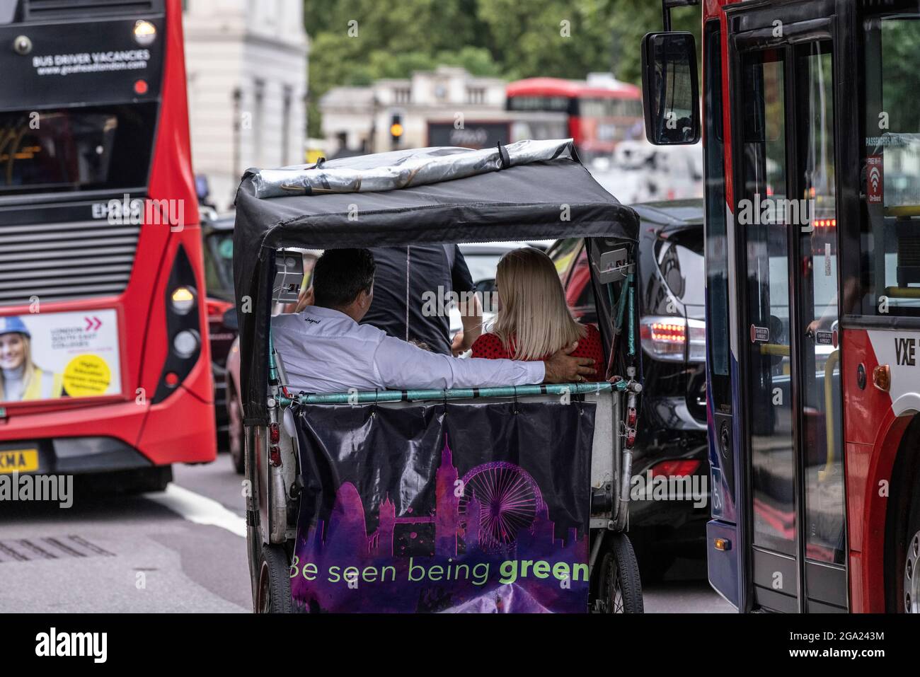 Un couple faire un tour et esquiver le trafic des heures de pointe dans un taxi-pousse à vélo, Hyde Park Corner, Londres, Angleterre, Royaume-Uni Banque D'Images