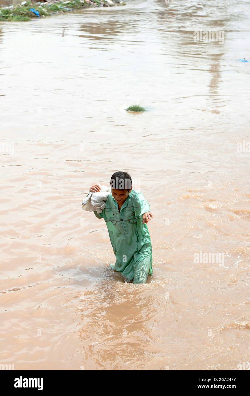 Islamabad. 28 juillet 2021. Un garçon traverse les eaux d'inondation après de fortes pluies à Islamabad, capitale du Pakistan, le 28 juillet 2021. Les autorités pakistanaises ont déclaré mercredi que de fortes pluies ont fait des ravages dans la capitale fédérale du pays, Islamabad, tuant au moins deux personnes et en blessant plusieurs autres. Crédit : Ahmad Kamal/Xinhua/Alamy Live News Banque D'Images