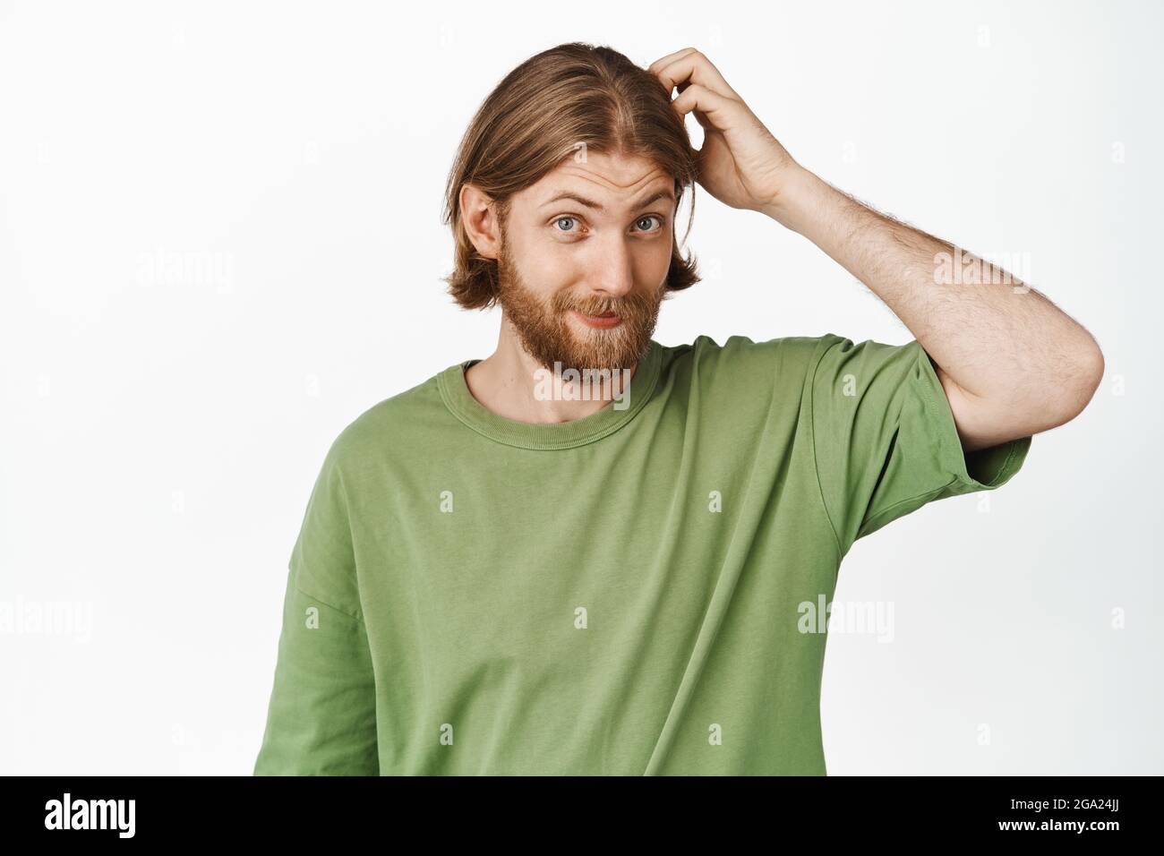 Image d'un beau type d'hipster, homme aux cheveux blonds et à la barbe,  sratching sa tête et sourire sans indice, debout dans un t-shirt vert  contre blanc Photo Stock - Alamy