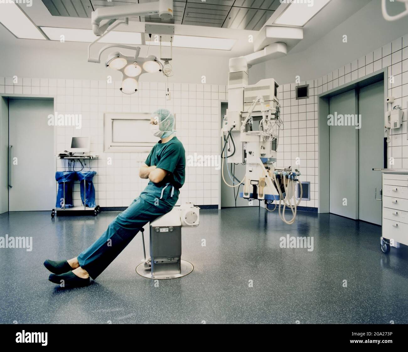 Le chirurgien est assis dans des exfoliants et un capuchon chirurgical à l'intérieur d'une salle d'opération ; Allemagne Banque D'Images