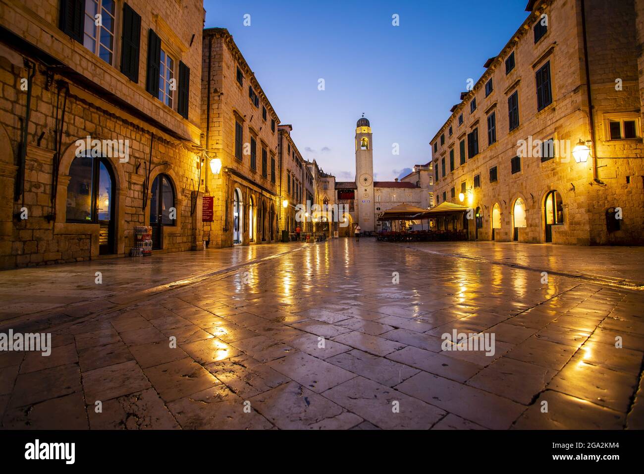 Lumière se reflétant sur les carreaux de pierre de la place Luza dans la vieille ville, en regardant vers le bas de la Tour de l'horloge contre le ciel de crépuscule ; Dubrovnik, Dalmatie, Croatie Banque D'Images