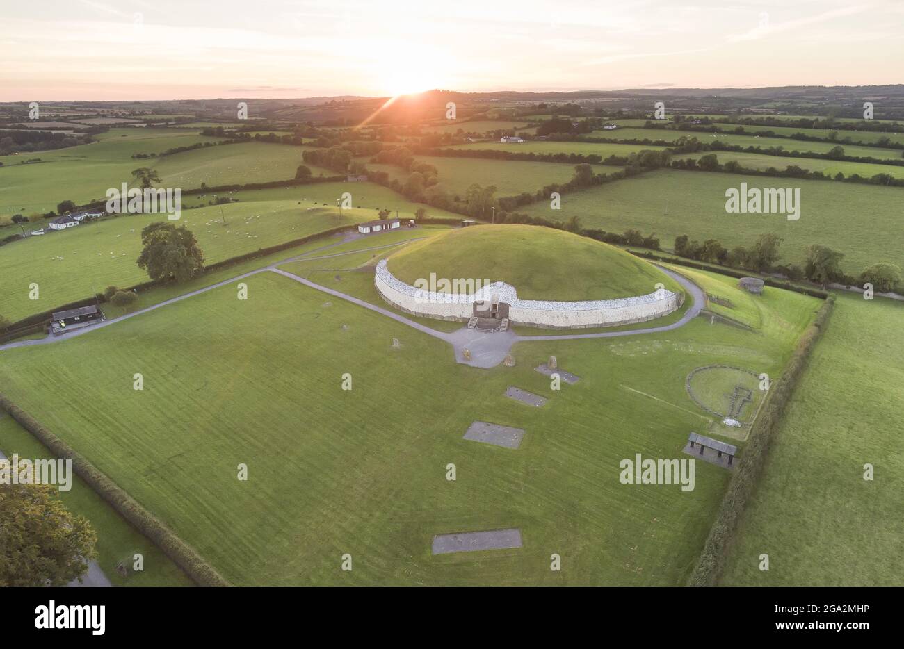 Vue aérienne d'un coucher de soleil et des terres agricoles environnantes sur l'ancien tombeau de passage et le temple de Newgrange, un monument néolithique à la Bru na Boinne sa... Banque D'Images