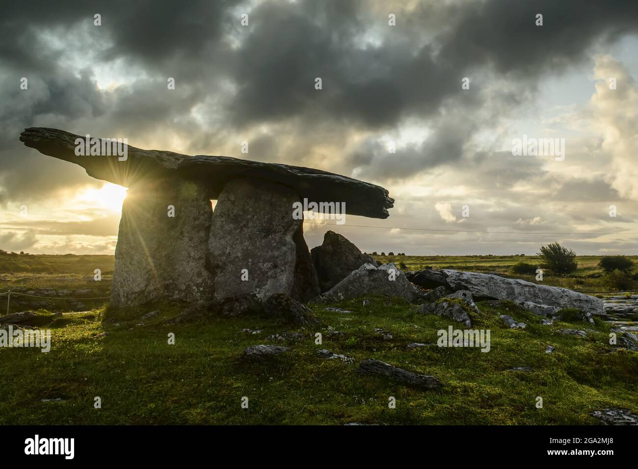 Le portail du dolmen tombeau de Poulnabrone avec le soleil d'or qui s'élève dans un ciel gris et nuageux sur le Burren; Comté de Clare, Irlande Banque D'Images