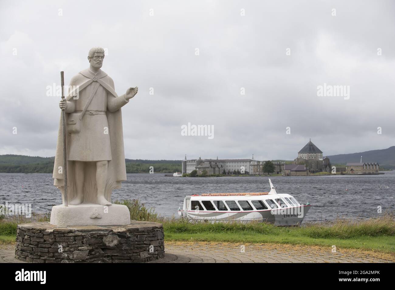 Statue de St Patrick et bateau sur les rives de Lough Derg, avec le site de Pilgrim du Purgatory de St Patrick sur Station Island en arrière-plan Banque D'Images