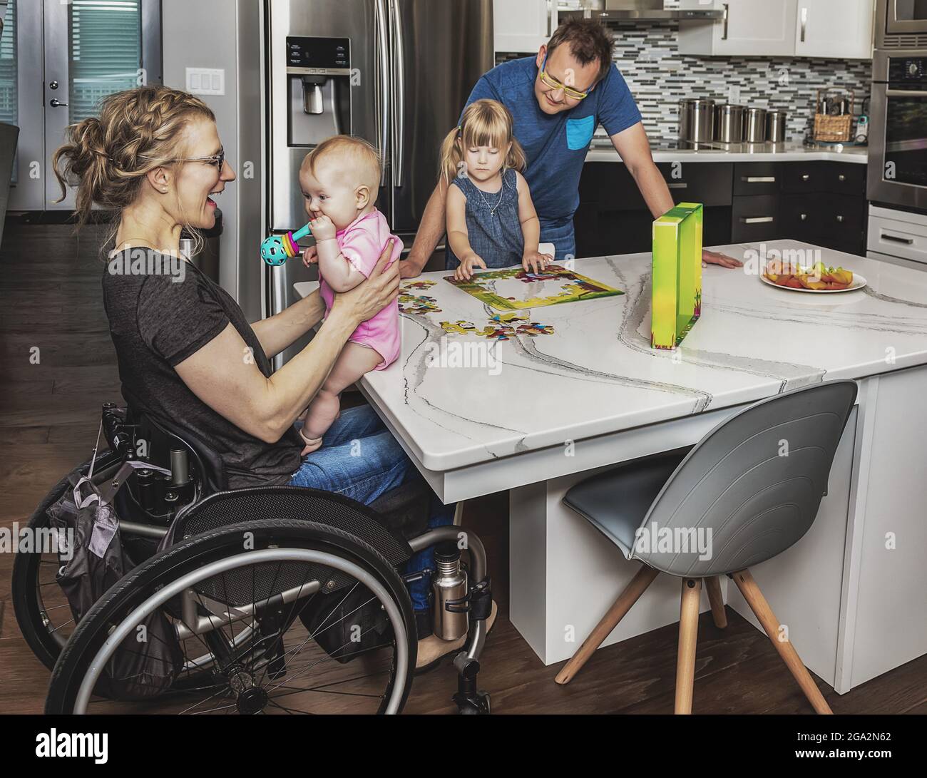 Une mère paraplégique et sa famille font un puzzle et passent du temps de qualité dans leur cuisine; Edmonton, Alberta, Canada Banque D'Images