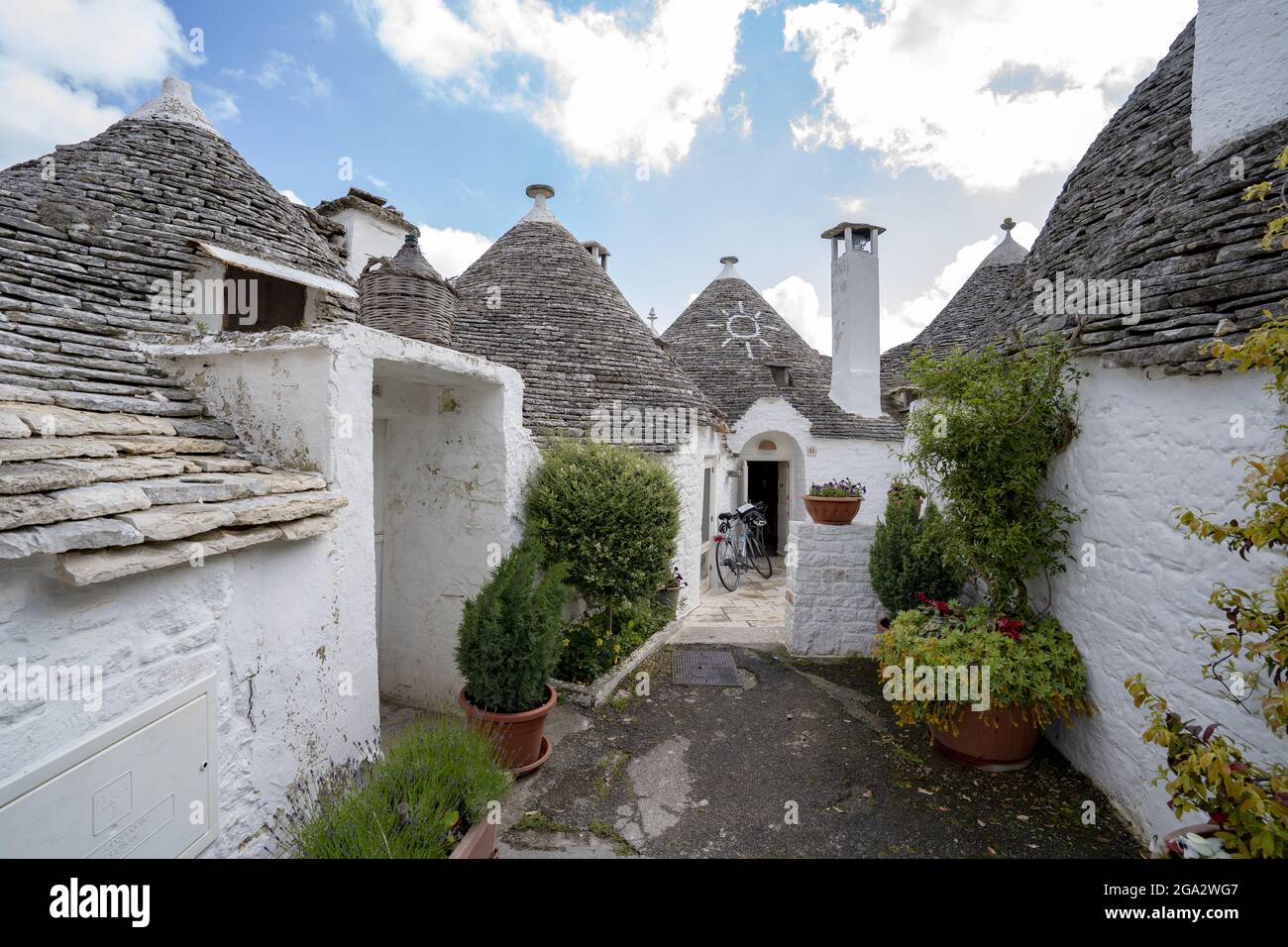 Plantes en pots et vélo dans la ruelle arrière des maisons traditionnelles en pierre ronde Trulli dans la ville d'Alberobello; Alberobello, Puglia, Italie Banque D'Images