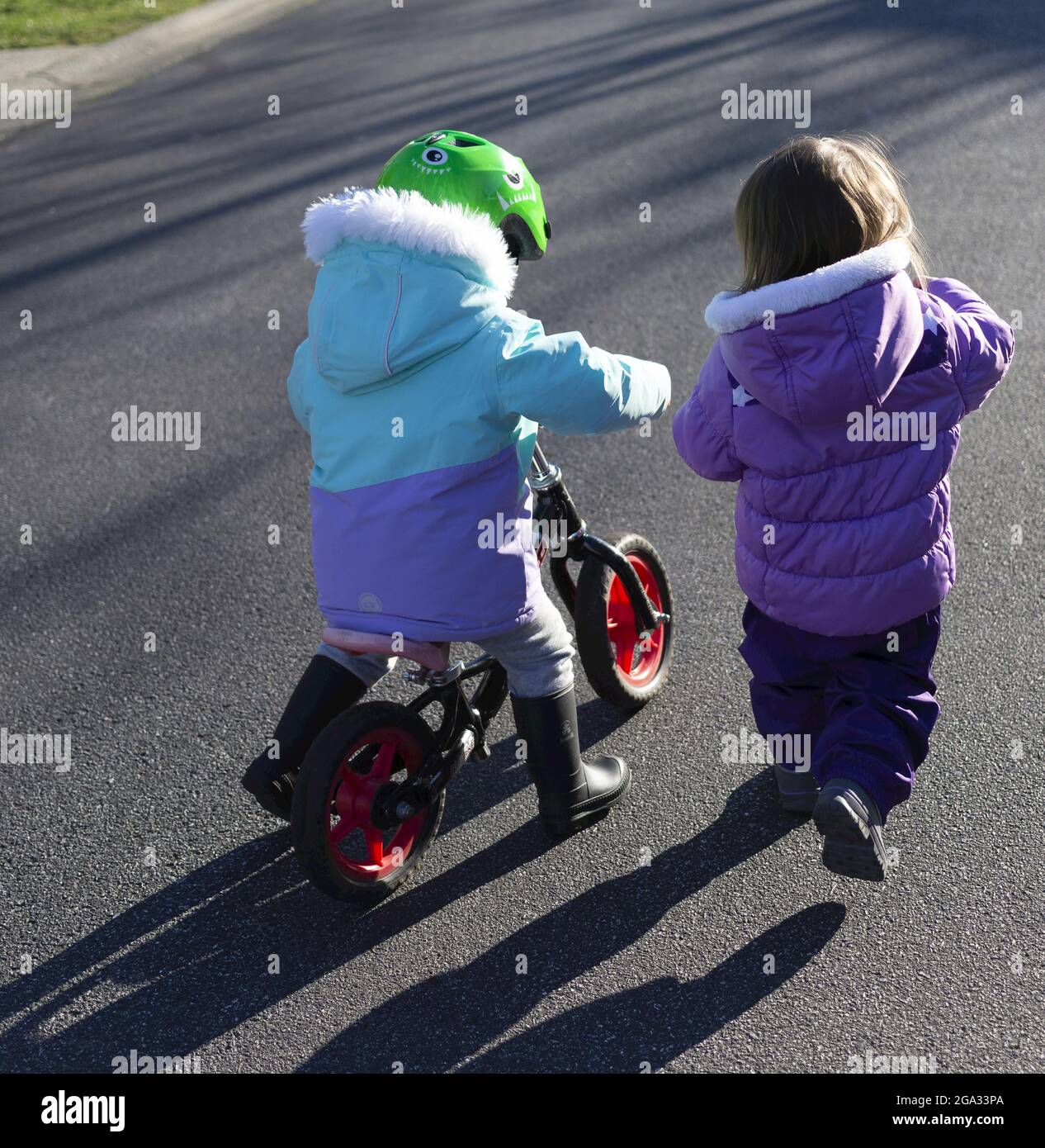 Deux jeunes filles ensemble à l'extérieur, l'une sur un planeur et l'autre à côté d'elle; Surrey, Colombie-Britannique, Canada Banque D'Images