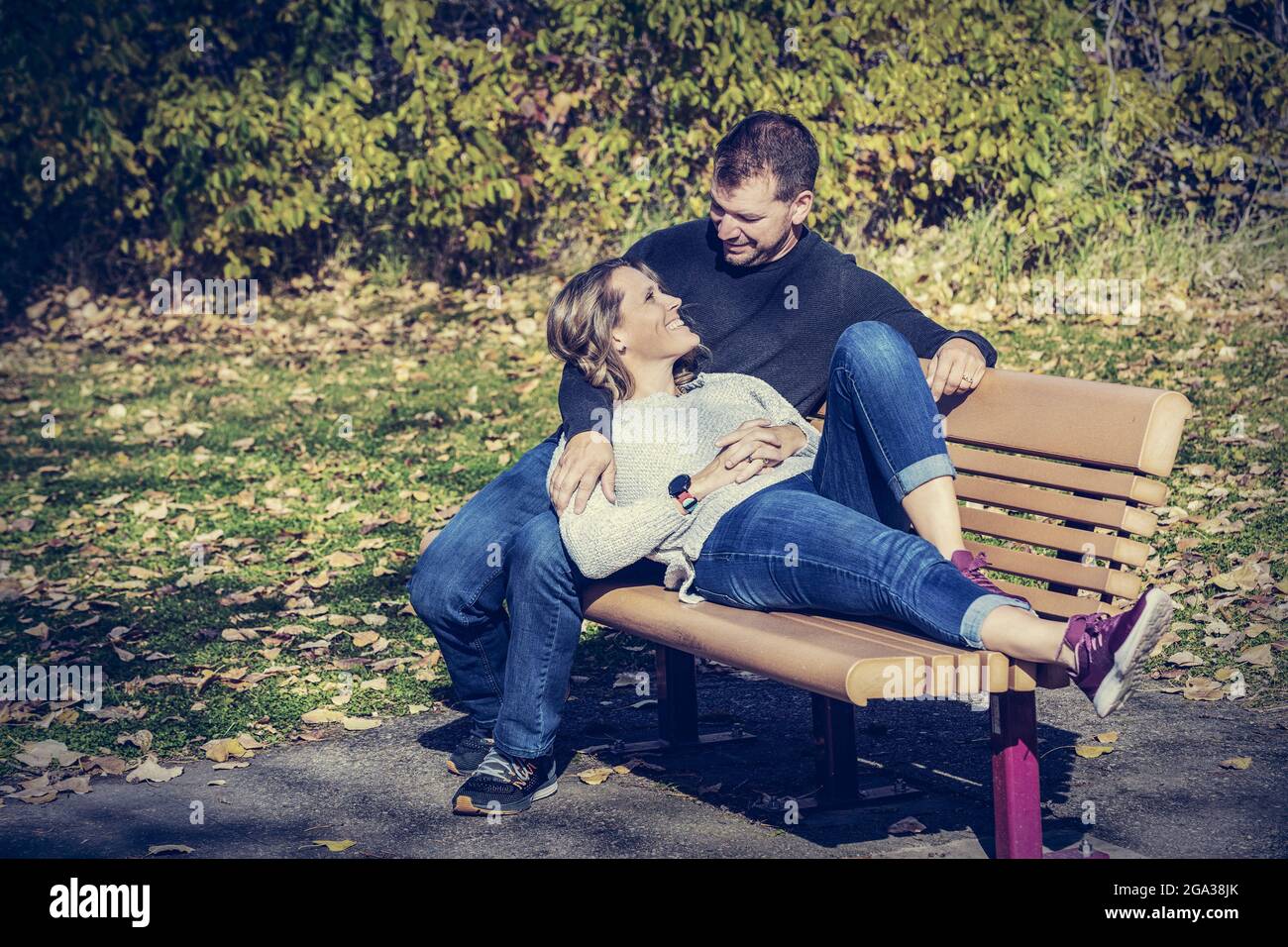 Un couple marié qui passe du temps ensemble de qualité à l'extérieur dans un parc de la ville pendant un après-midi d'automne chaud; St. Albert, Alberta, Canada Banque D'Images