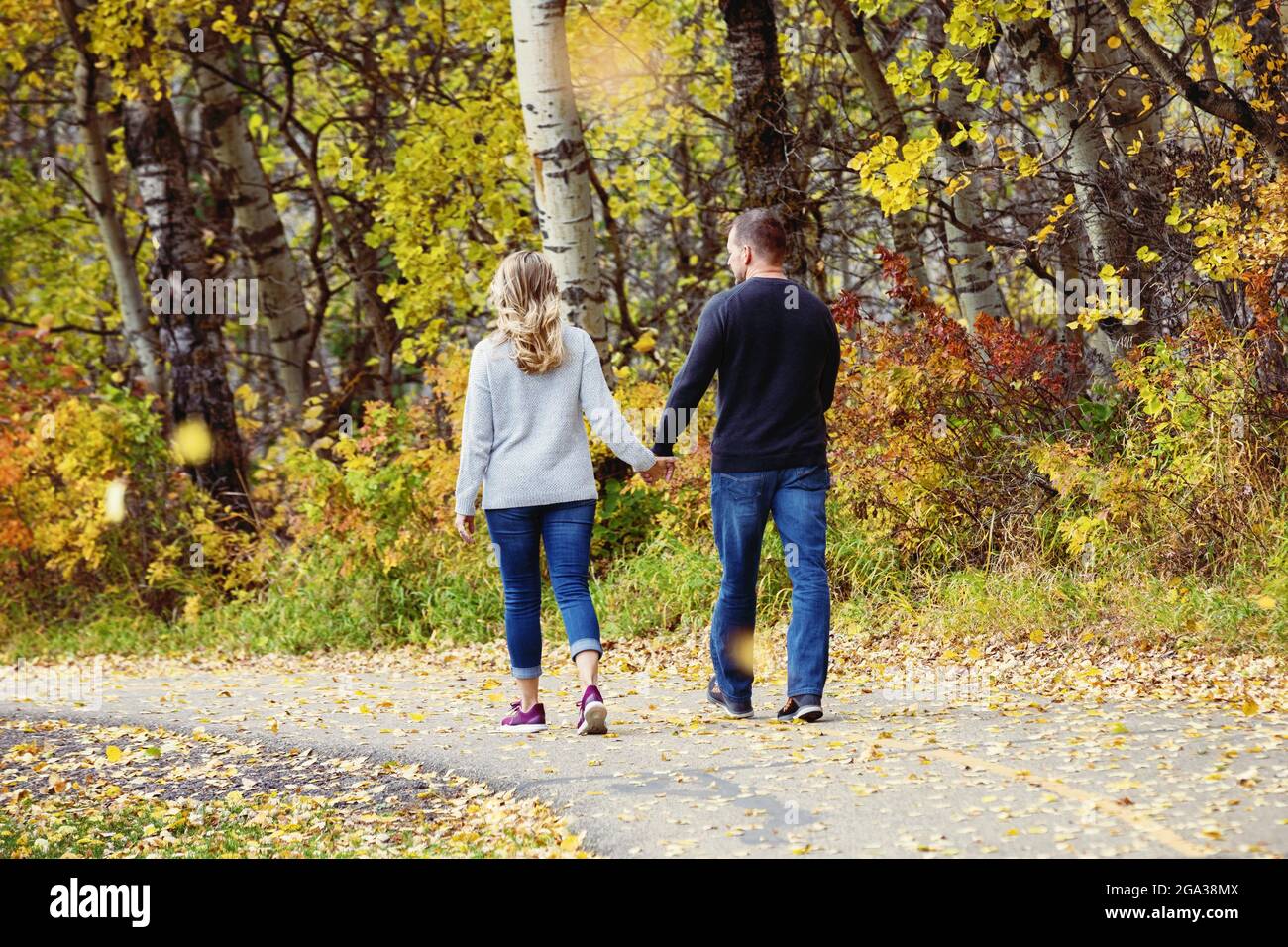 Un couple marié mature qui passe du temps ensemble de qualité à marcher à l'extérieur dans un parc de la ville pendant un après-midi d'automne chaud; St. Albert, Alberta, Canada Banque D'Images