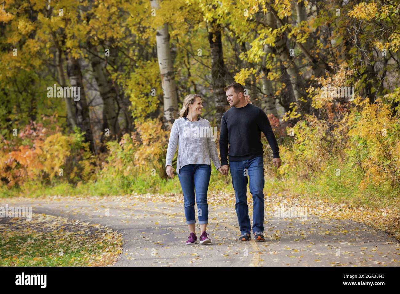 Un couple marié mature qui passe du temps ensemble de qualité à marcher à l'extérieur dans un parc de la ville pendant un après-midi d'automne chaud; St. Albert, Alberta, Canada Banque D'Images