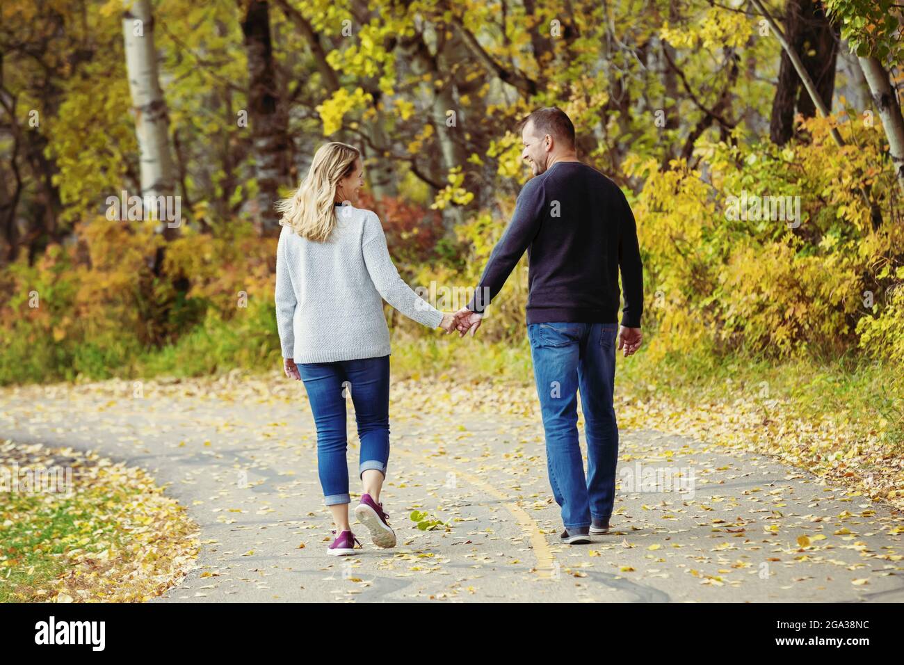 Un couple marié mature qui passe du temps ensemble de qualité à marcher à l'extérieur dans un parc de la ville pendant un après-midi d'automne chaud; St. Albert, Alberta, Canada Banque D'Images