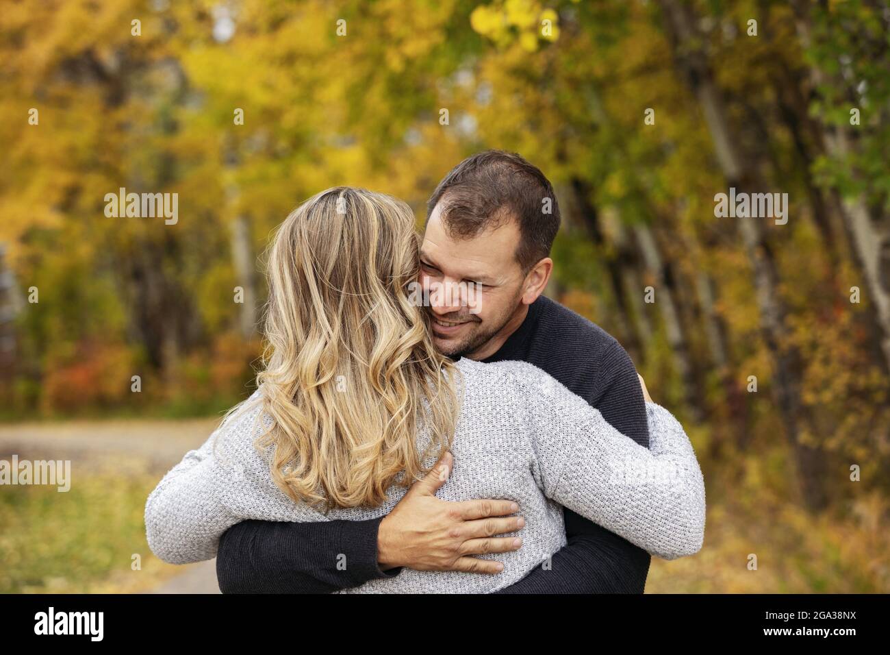 Un couple marié dans une étreinte tout en passant du temps de qualité ensemble à l'extérieur dans un parc de la ville pendant un après-midi d'automne chaud; St. Albert, Alberta, Canada Banque D'Images