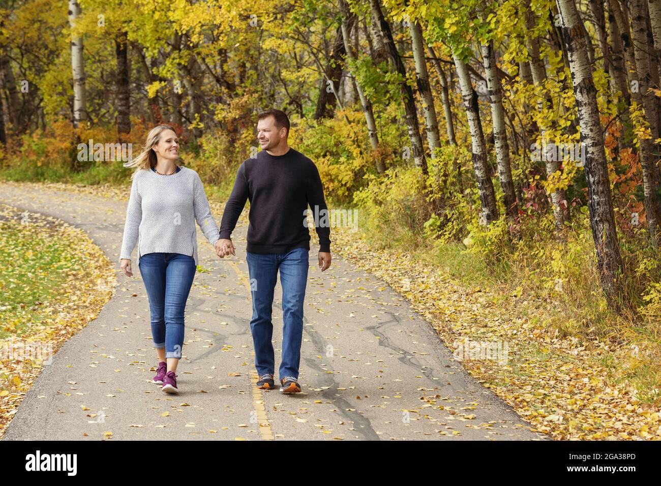 Un couple marié mature qui passe du temps ensemble de qualité à marcher à l'extérieur dans un parc de la ville pendant un après-midi d'automne chaud; St. Albert, Alberta, Canada Banque D'Images