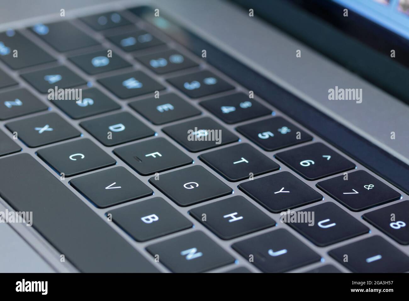 gros plan macro avec une faible profondeur de champ d'un clavier d'ordinateur avec touches noires, lettres blanches et corps gris, avec touches rétroéclairées en bleu clair Banque D'Images