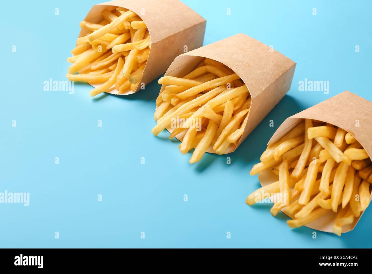 Boîtes en papier contenant de savoureuses frites sur fond de couleur Banque D'Images