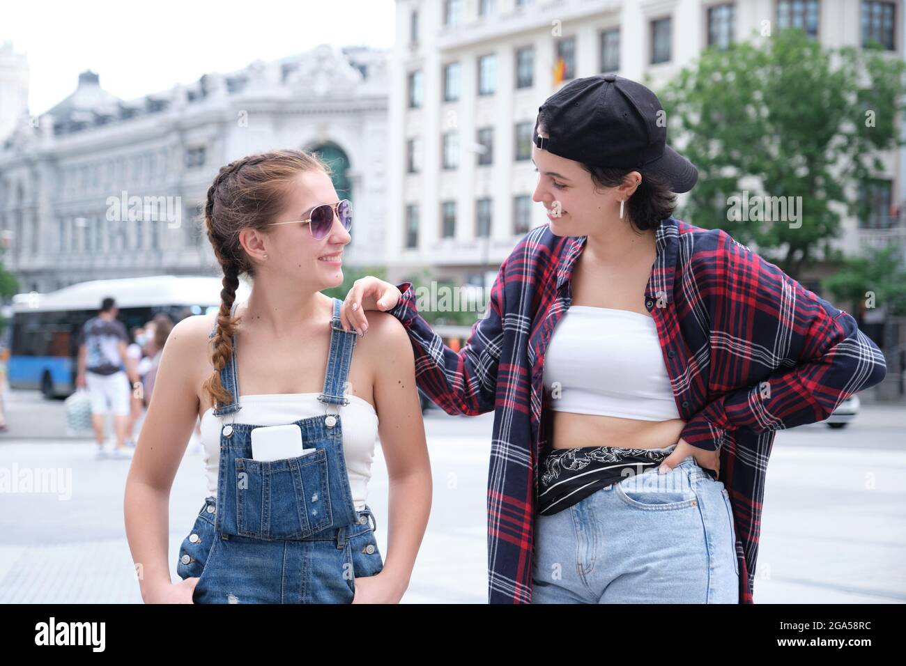 Deux femmes sympa souriant et regardant l'une l'autre. Deux amies qui se posent dans la rue. Banque D'Images