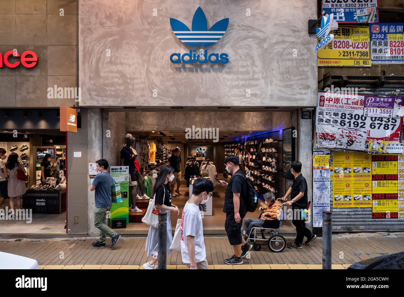 Hong Kong, Chine. 28 juillet 2021. Des piétons marchent devant la marque allemande multinationale de vêtements de sport Adidas magasin et logo à Hong Kong. Crédit : SOPA Images Limited/Alamy Live News Banque D'Images