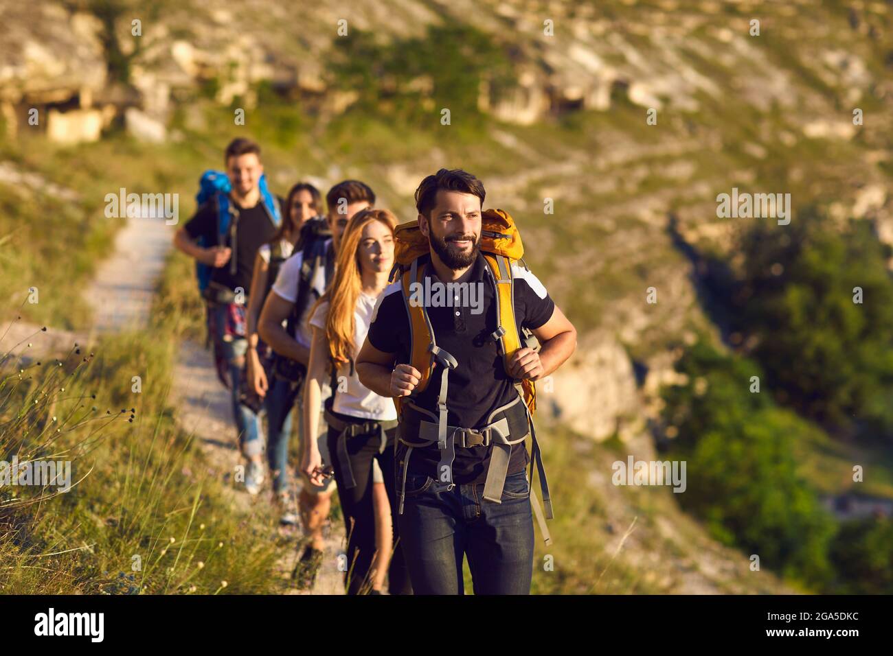 Groupe de jeunes touristes randonneurs marchant le long de la vallée de la montagne pendant le voyage Banque D'Images