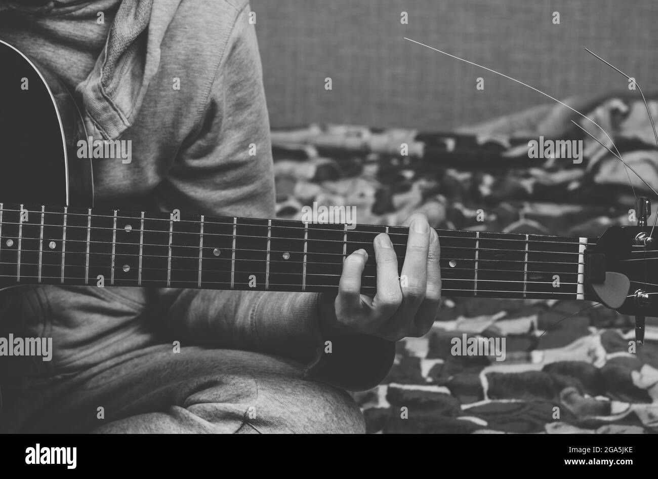 La femme joue de la guitare. La main saisit les cordes sur le tableau de fretboard Banque D'Images