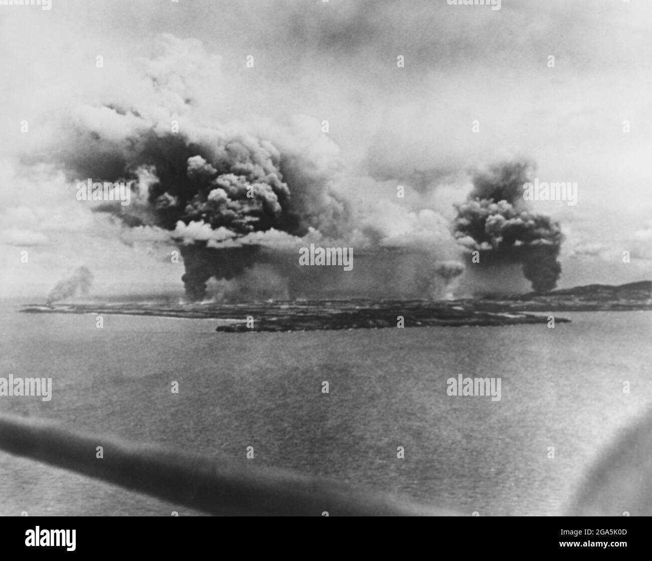 Guerre du Pacifique : une décharge de carburant et une raffinerie de sucre brûlent après une frappe aérienne américaine sur l'île de Saipan le 16 juin 1944. La bataille de Saipan (du 15 juin au 9 juillet 1944) était une bataille clé du Pacifique pendant la Seconde Guerre mondiale, menée entre les forces armées des États-Unis et du Japon Banque D'Images