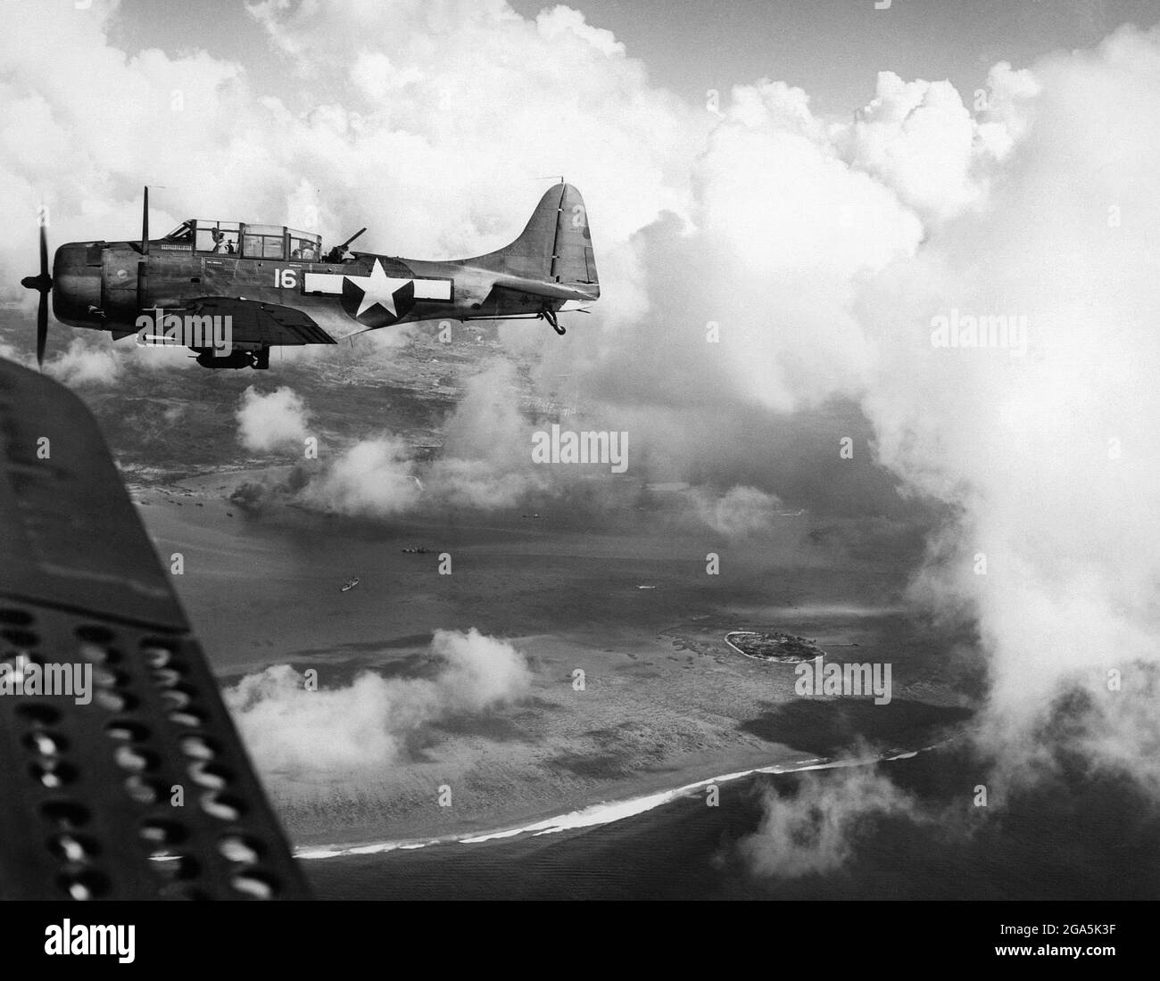 Guerre du Pacifique : un bombardier américain Douglas SBD Dauntless survole l'île de Saipan le 15 juin 1944. La bataille de Saipan (du 15 juin au 9 juillet 1944) était une bataille clé du Pacifique pendant la Seconde Guerre mondiale, menée entre les forces armées des États-Unis et du Japon. Banque D'Images
