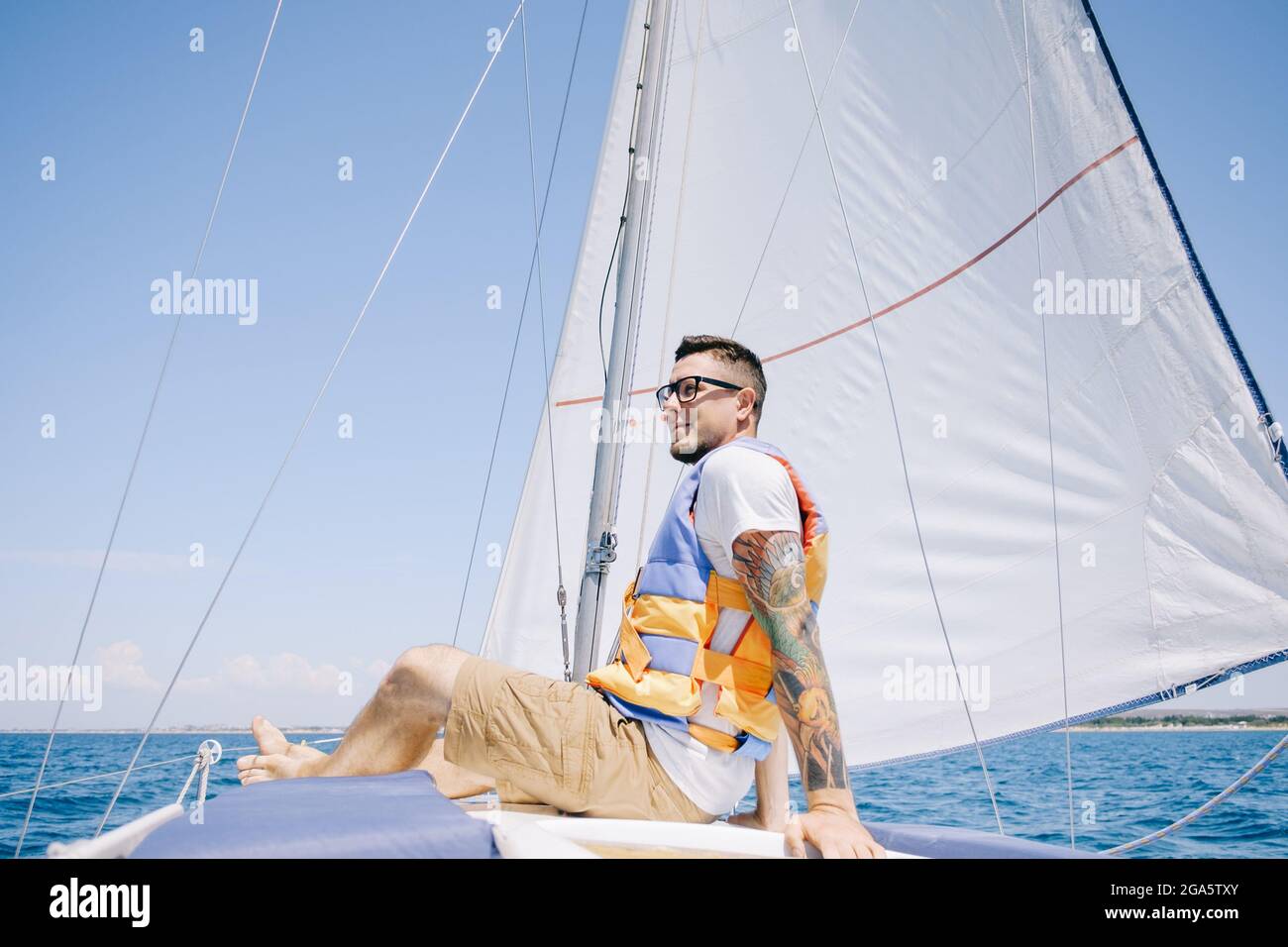 Un homme heureux est assis sur l'arc du yacht. Banque D'Images