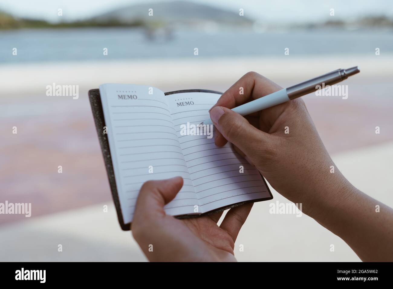 Femme écriture manuelle dans petit bloc-notes blanc pour prendre une note à ne pas oublier ou pour faire la liste de planification pour l'avenir. Banque D'Images
