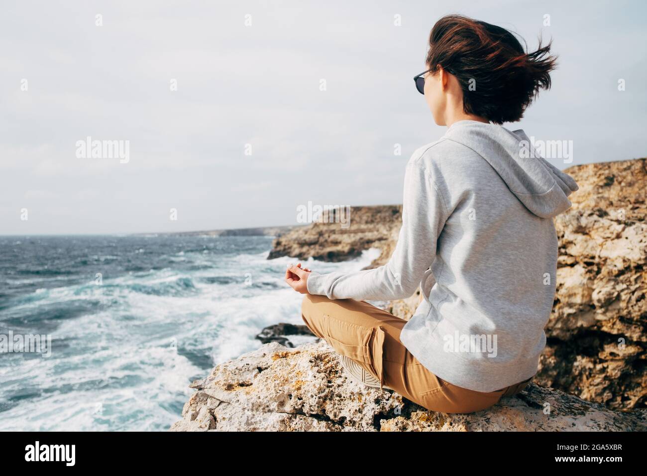 La femme est assise dans une position de lotus et pratique la méditation près du bord de mer. Banque D'Images