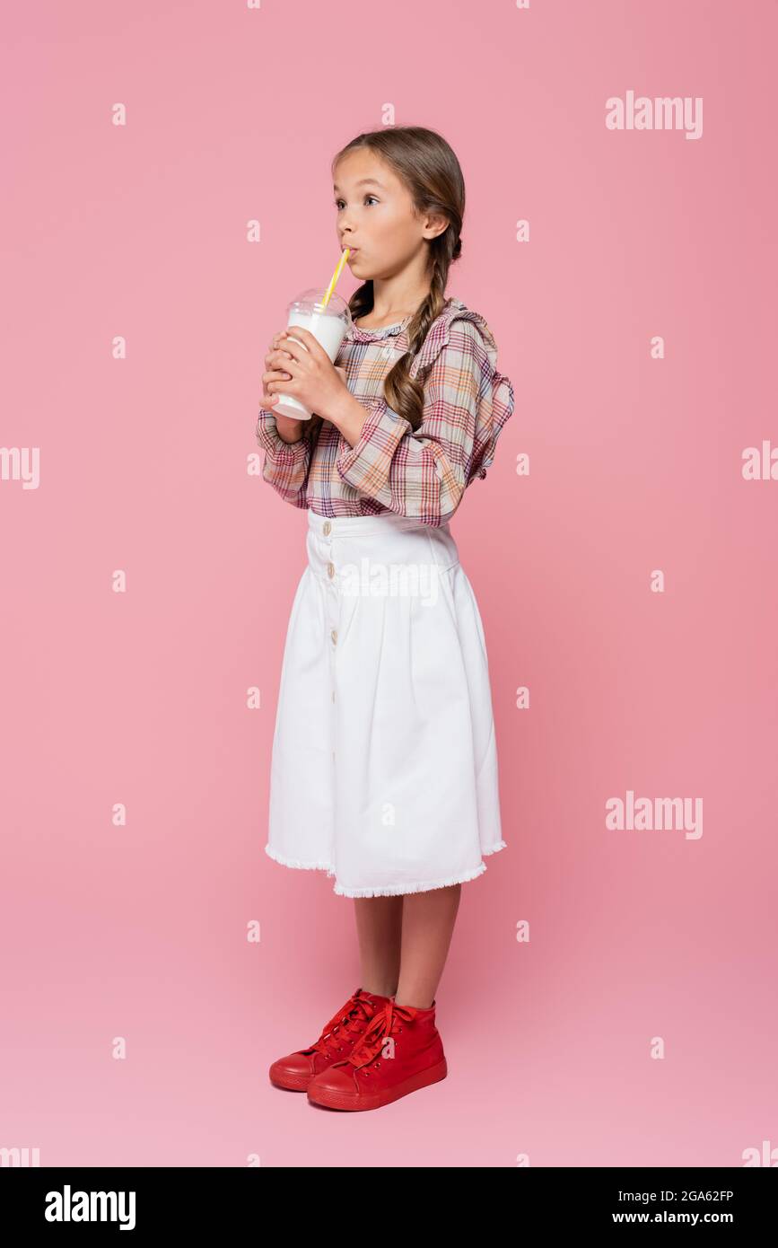 Une jeune fille élégante qui boit du milkshake sur fond rose Banque D'Images