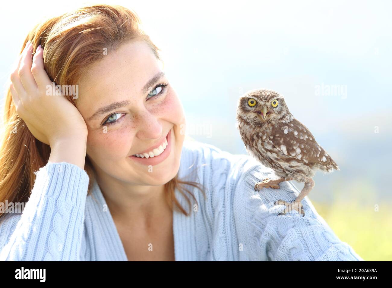 Belle femme avec les yeux bleus posant avec un owlet regardant la caméra Banque D'Images