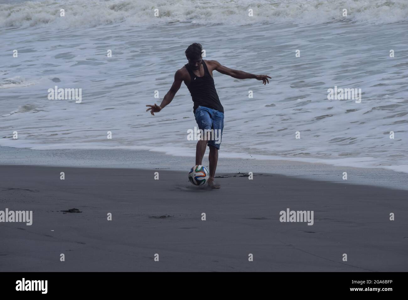 Homme jouant au football sur la plage seulement. Banque D'Images