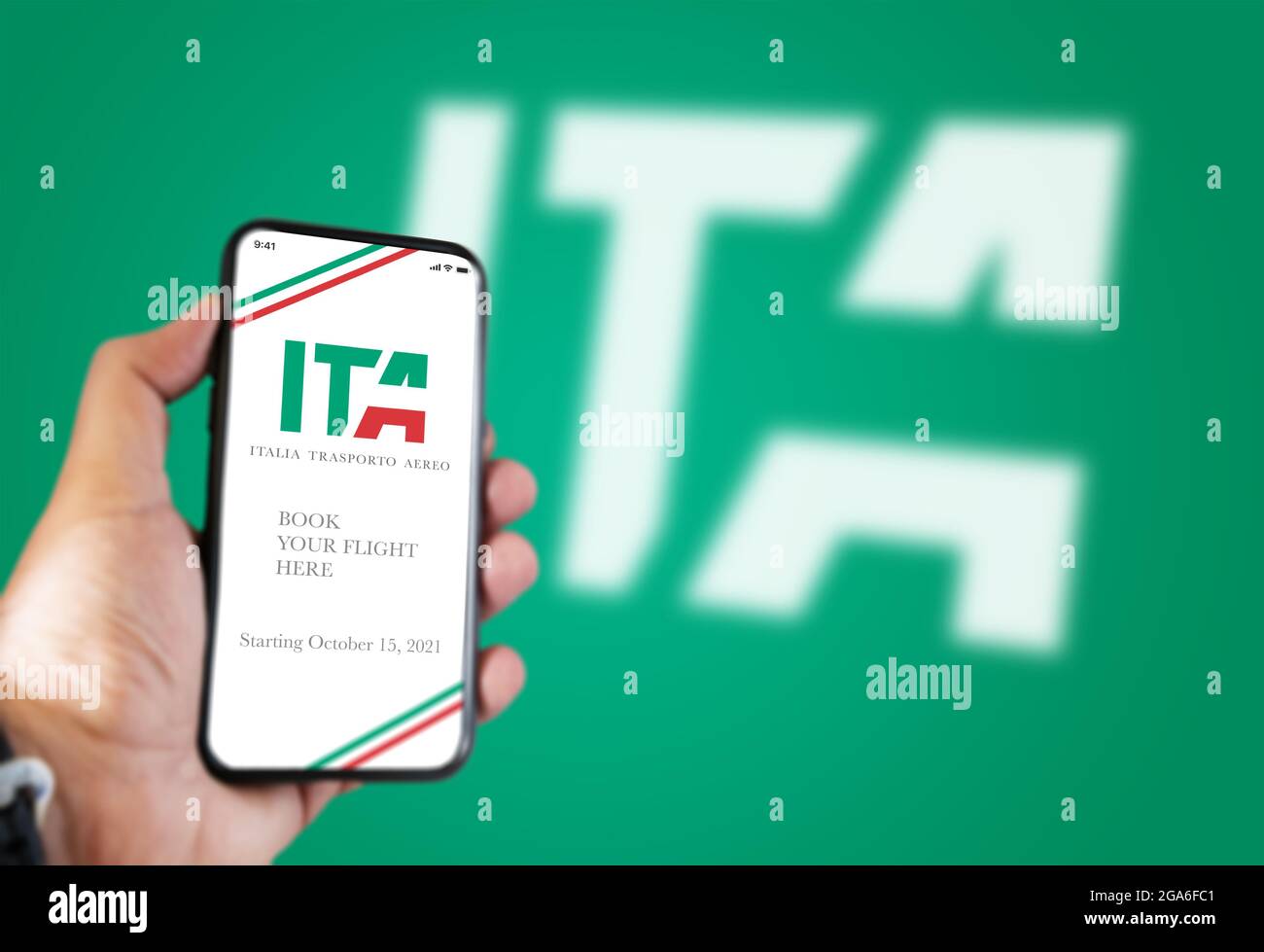 Rome, Italie, juillet 2021: Une main tenant un téléphone avec l'application ITA sur l'écran et le logo ITA flou sur un fond vert.ITA est la nouvelle fl italienne Banque D'Images