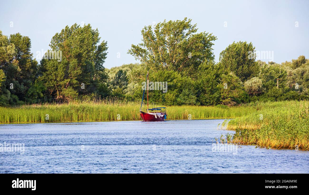 Image d'un yacht rouge naviguant le long de la rive de la rivière Reed Banque D'Images