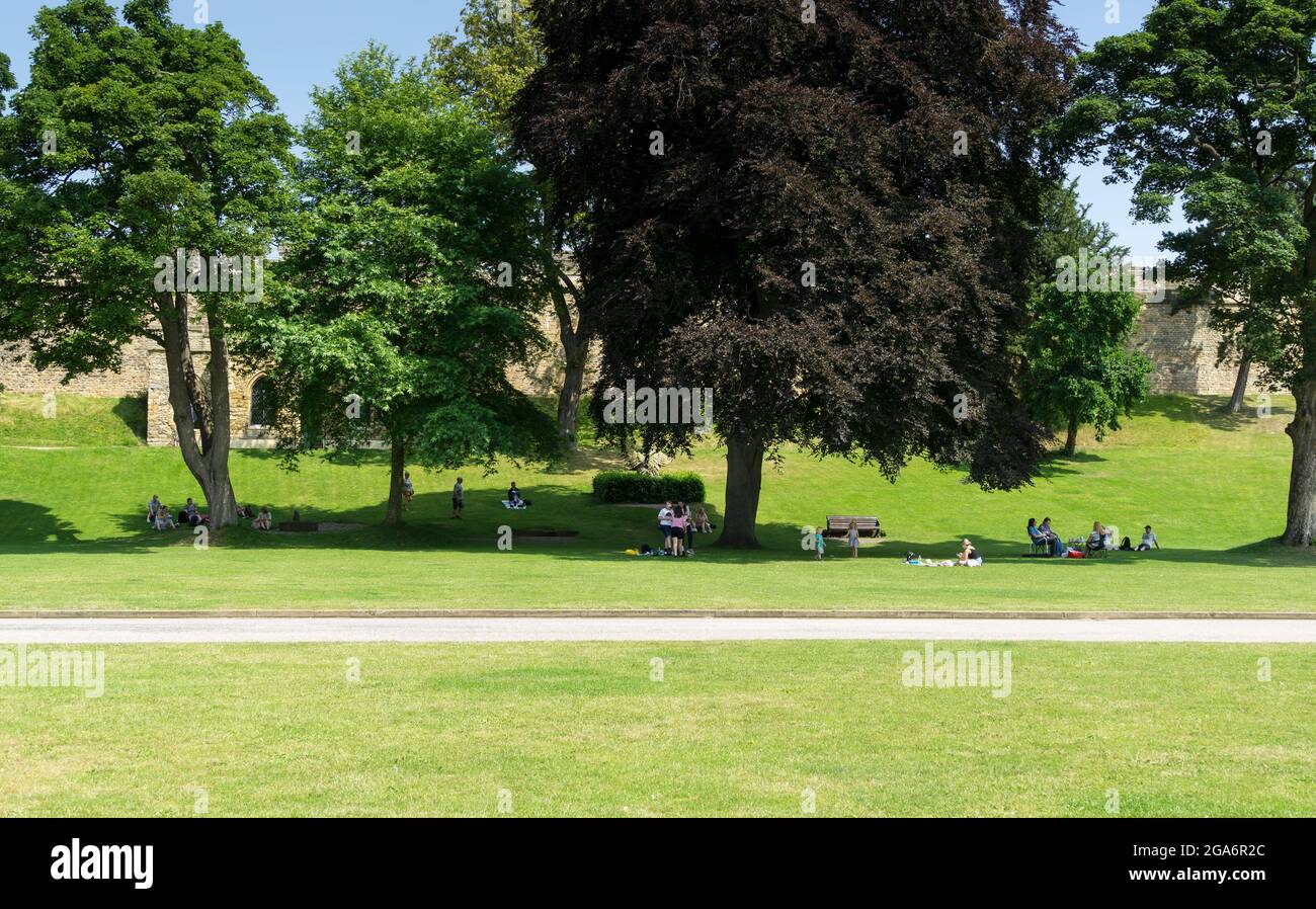 Les gens pique-niques à l'ombre des arbres sous le soleil chaud dans le parc du château Lincoln Lincolnshire 2021 Banque D'Images
