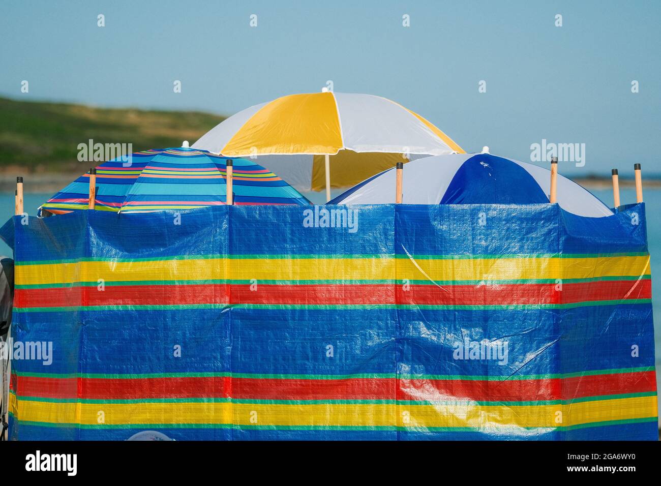 Parapluies de plage et de brise-vent offrant ombre, abri et intimité sur une plage britannique. Banque D'Images