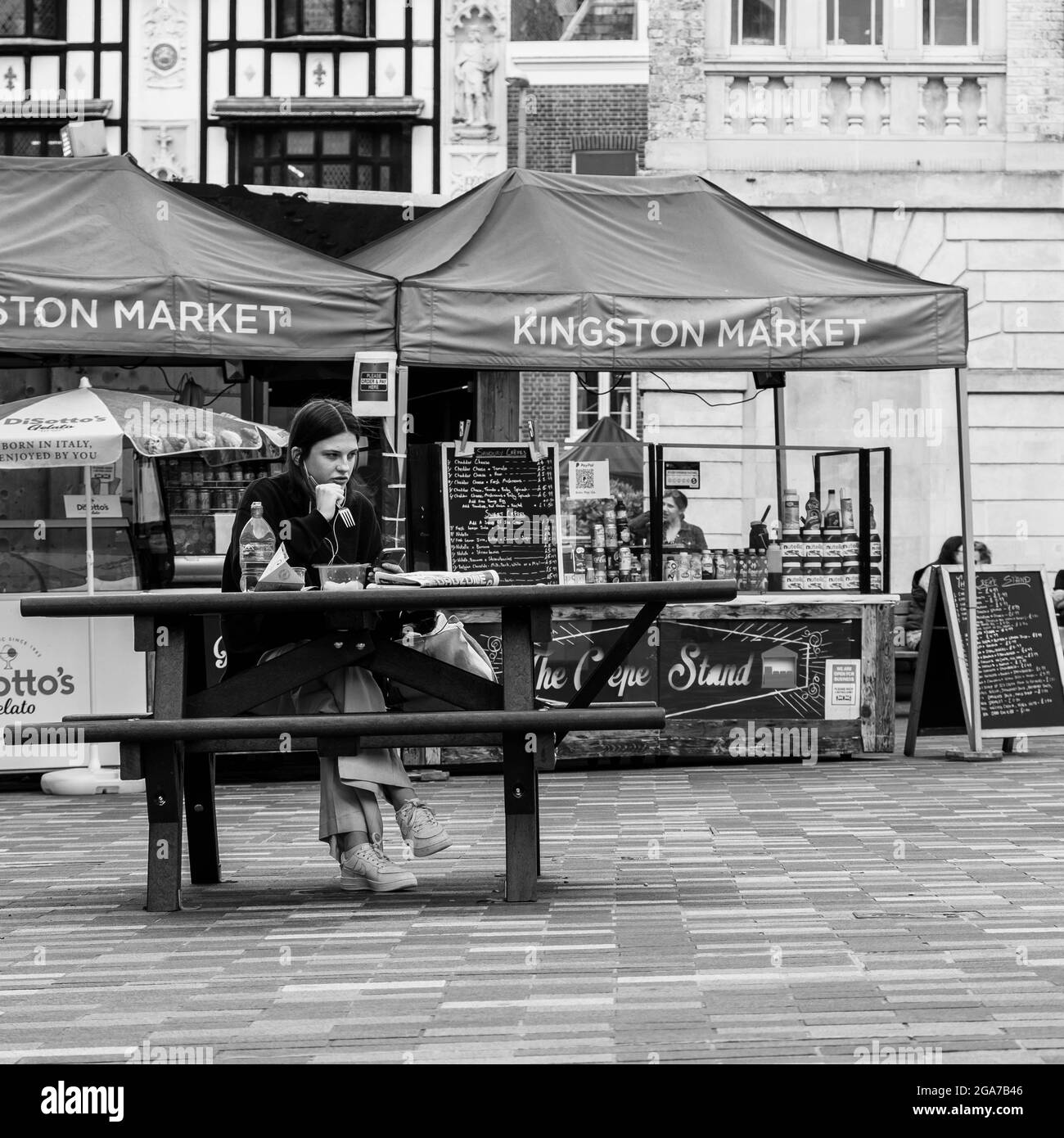 Kingston Surrey London, le 2021 juin, une jeune femme qui pique à un banc repas seul en noir et blanc Banque D'Images
