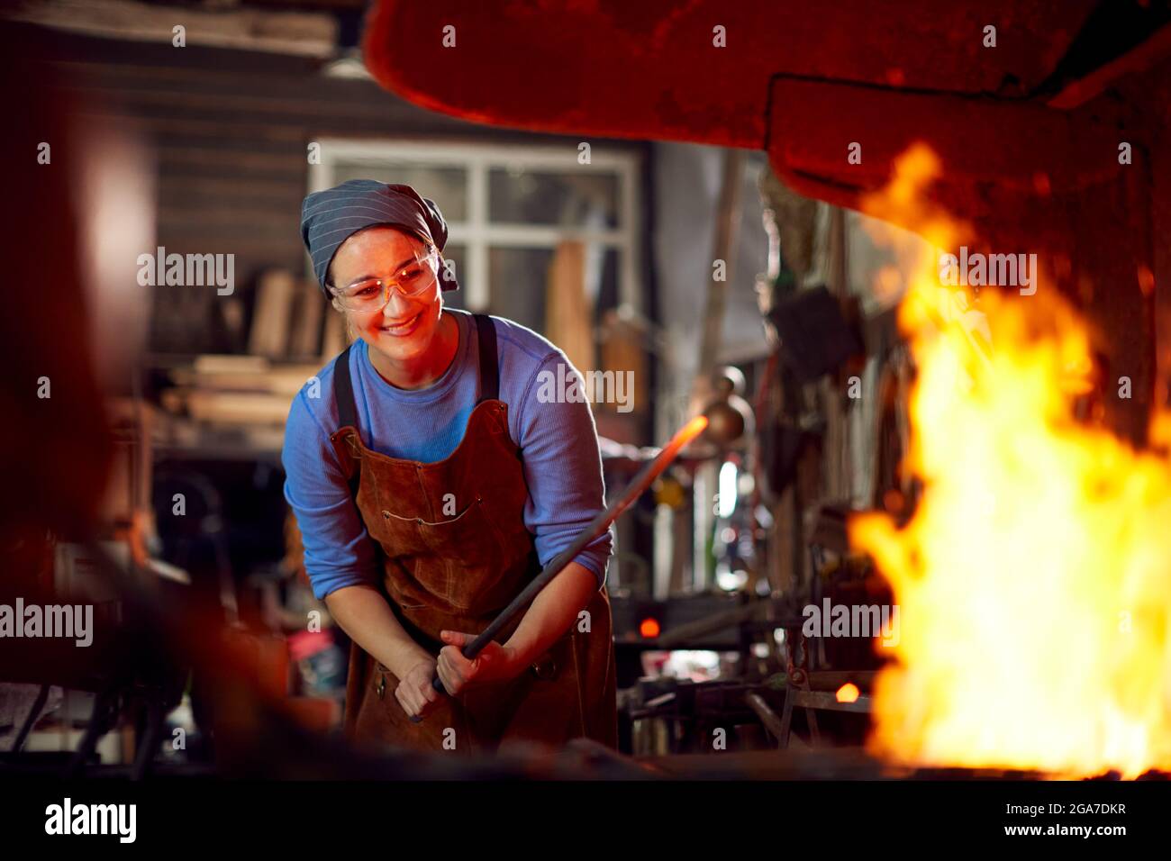 Femme Blacksmith chauffant Metalwork dans Flames of Forge Banque D'Images