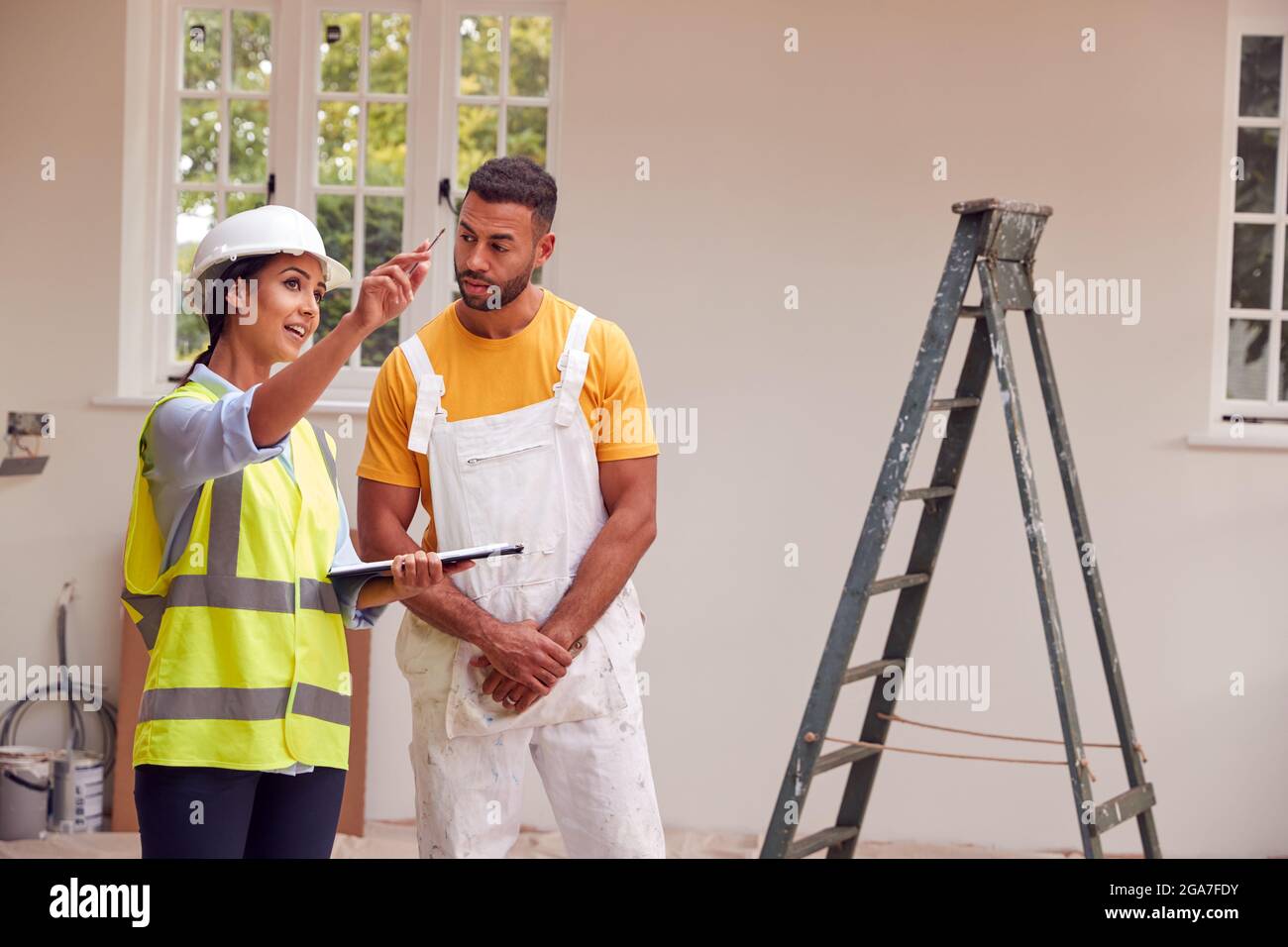 Femme Surveyor avec presse-papiers Réunion avec Décorateur travaillant à l'intérieur de la propriété Banque D'Images