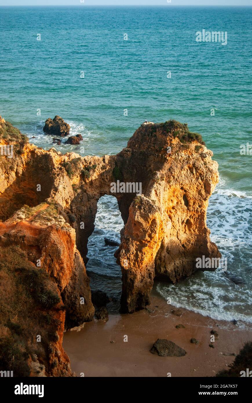 Arche naturelle au coucher du soleil sur la côte du Portugal - des rochers de couleur orange forment une arche sur la plage Banque D'Images
