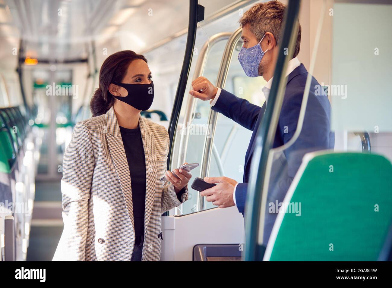 Les voyageurs d'affaires se trouvent dans un train avec des téléphones mobiles portant un masque facial PPE pendant une pandémie Banque D'Images
