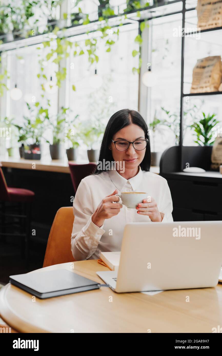 Portrait de belles femmes d'affaires appréciant le café pendant le travail sur un ordinateur portable tout en étant assis dans un café. Banque D'Images