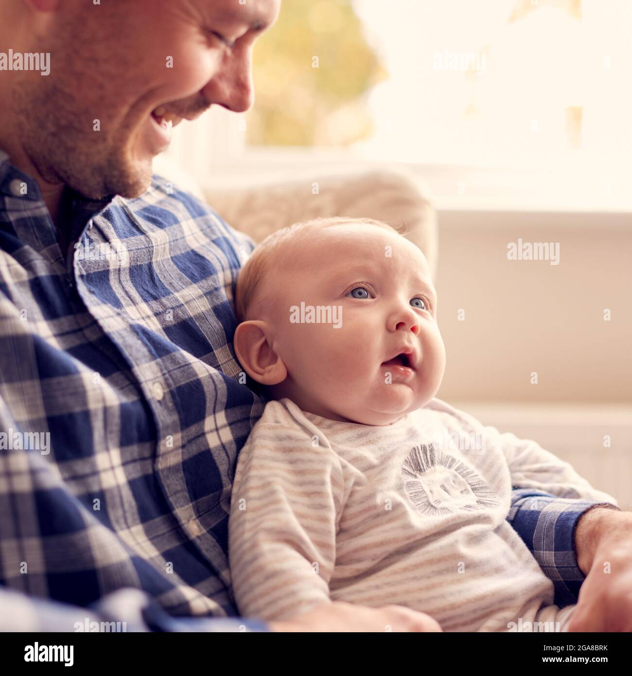 Gros plan du Père qui câlin bébé fils assis sur les genoux dans la chaise  longue à la maison ensemble Photo Stock - Alamy