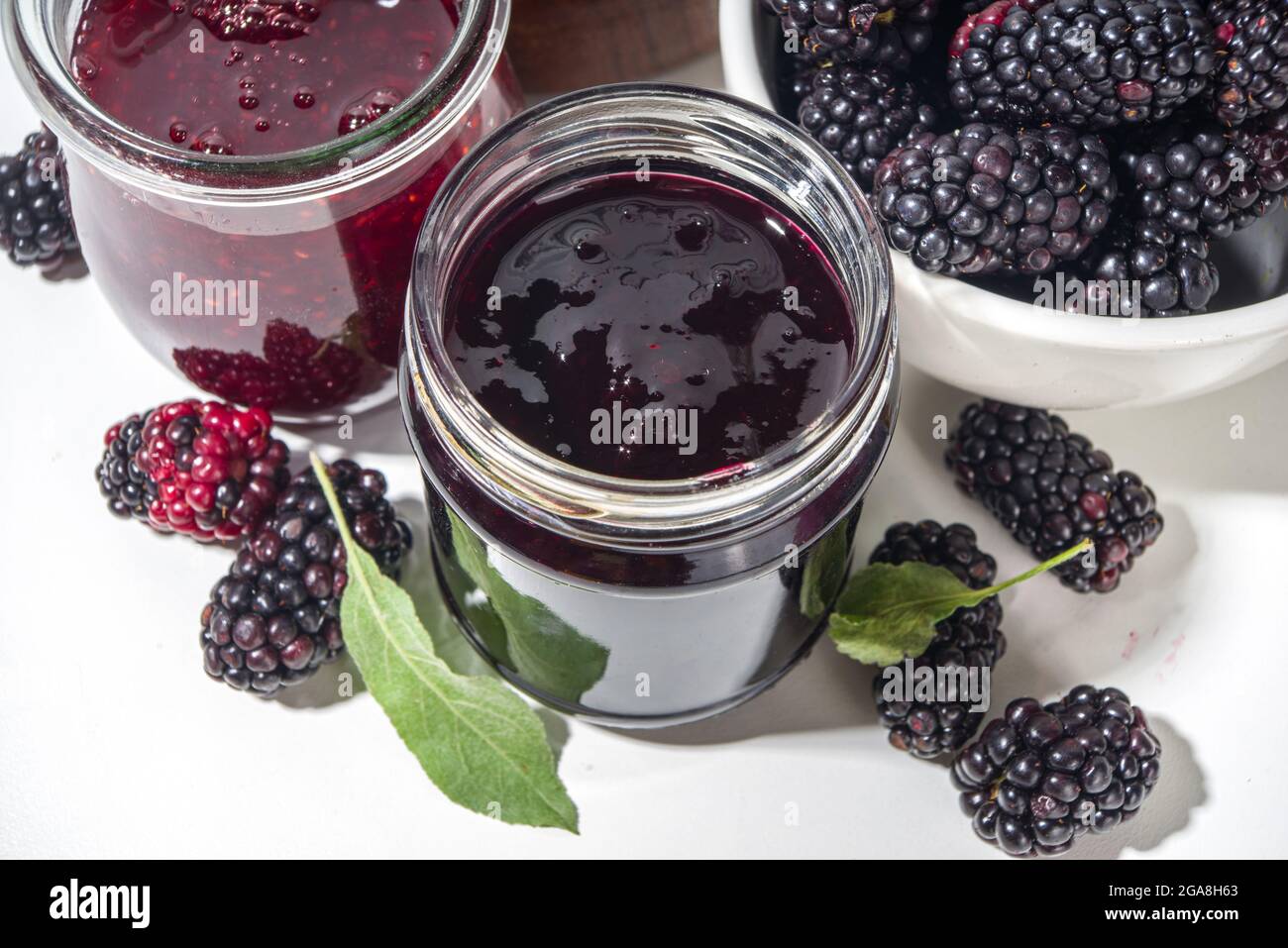 Confiture de mûres maison dans un petit pot en verre sur fond blanc, avec un espace de copie de baies fraîches Banque D'Images