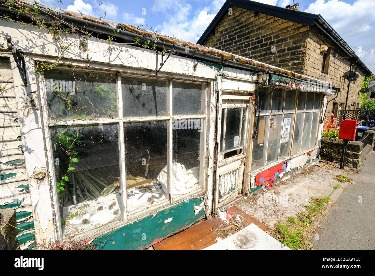 Un magasin de façade abandonné dans le village de Stoney Middleton dans le Derbyshire. Les fenêtres cassées, les cadres en décomposition et la peinture écaillée présentent une triste image d'un emplacement. Banque D'Images