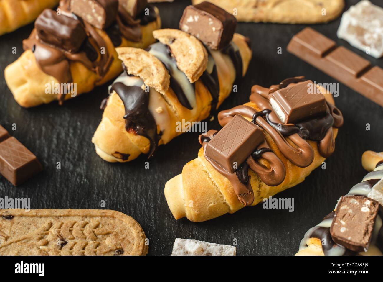 Gros plan sur les croissants sucrés faits maison sur la plaque noire avec biscuit au chocolat et crème sur la table Banque D'Images