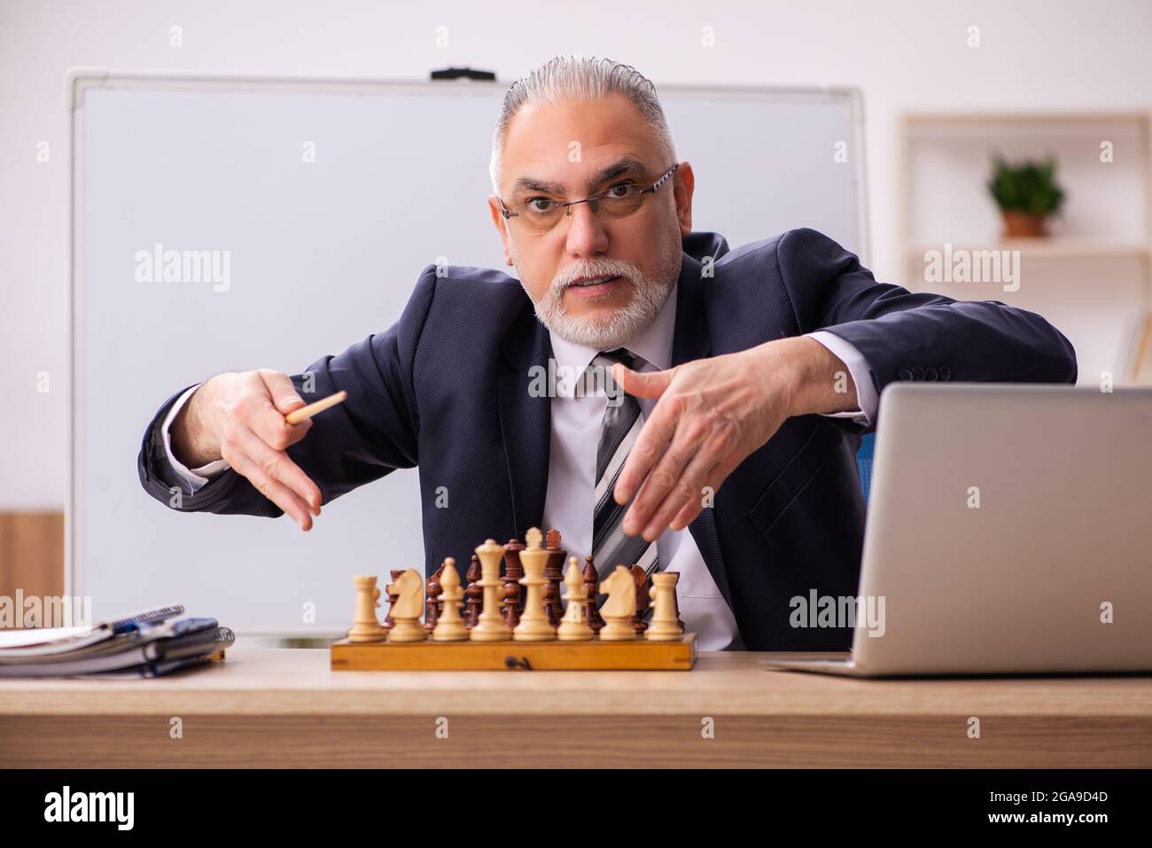 Un vieux employé d'homme d'affaires jouant aux échecs sur le lieu de travail Banque D'Images