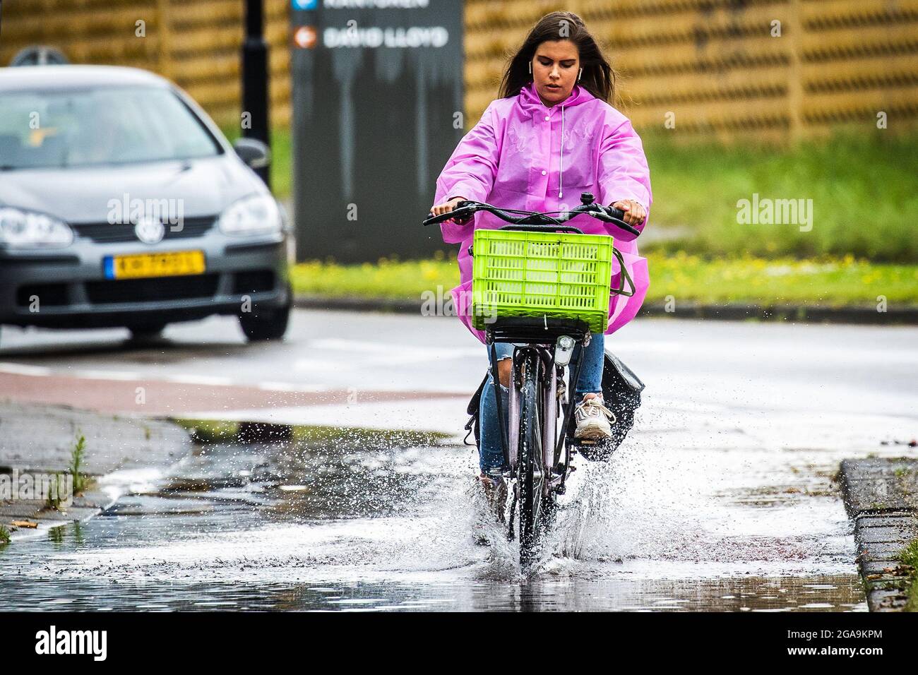 DORDRECHT - 27-07-2021. Fietsers en scooters rijden sur een met eau  ondergelopen fietspad à Dordrecht. Fietsers en mensen op de scooter rijden  door de regen en plassen op een fietspad. Code geel