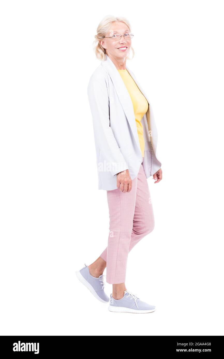 Photo verticale pleine longueur d'une femme caucasienne âgée portant une tenue de marche élégante, fond blanc Banque D'Images